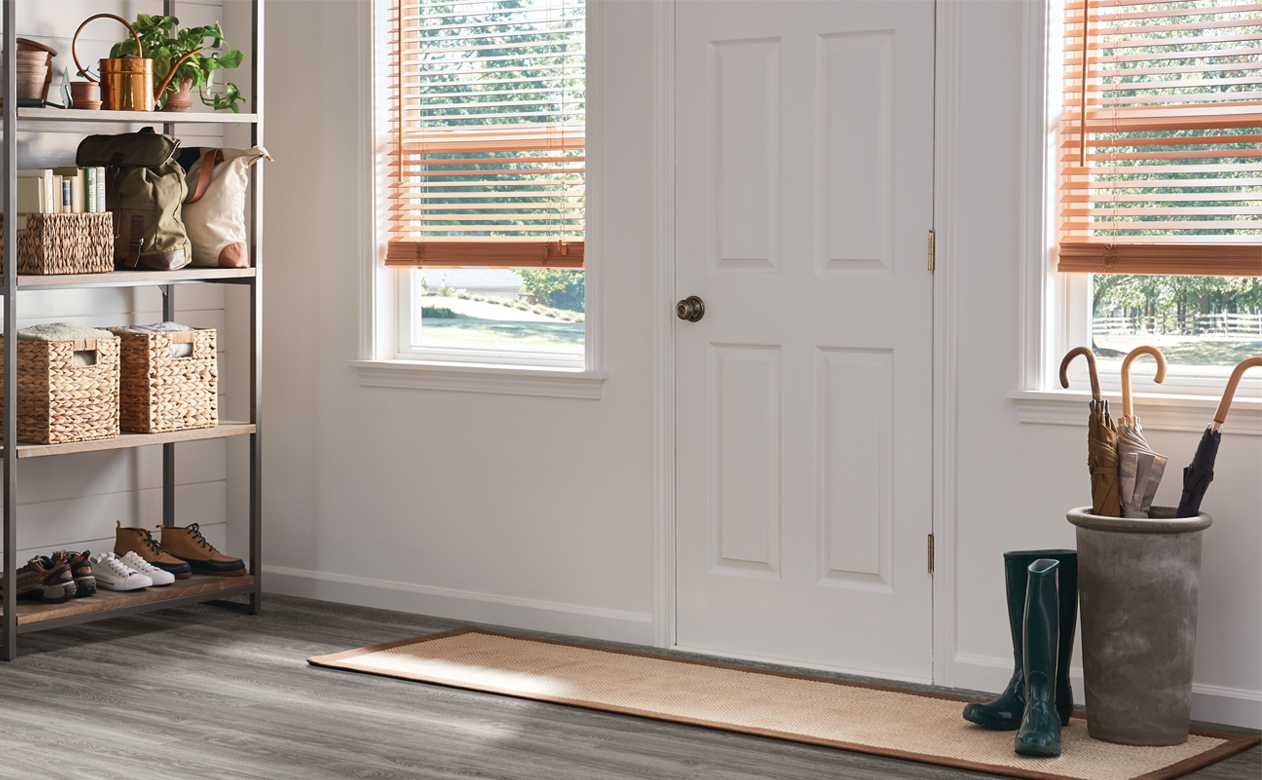 wood blinds in entryway front door hall with gray wood-look flooring